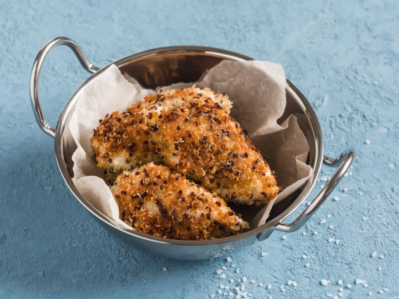 Frango empanado com quinoa em recipiente de alumínio com papel-manteiga