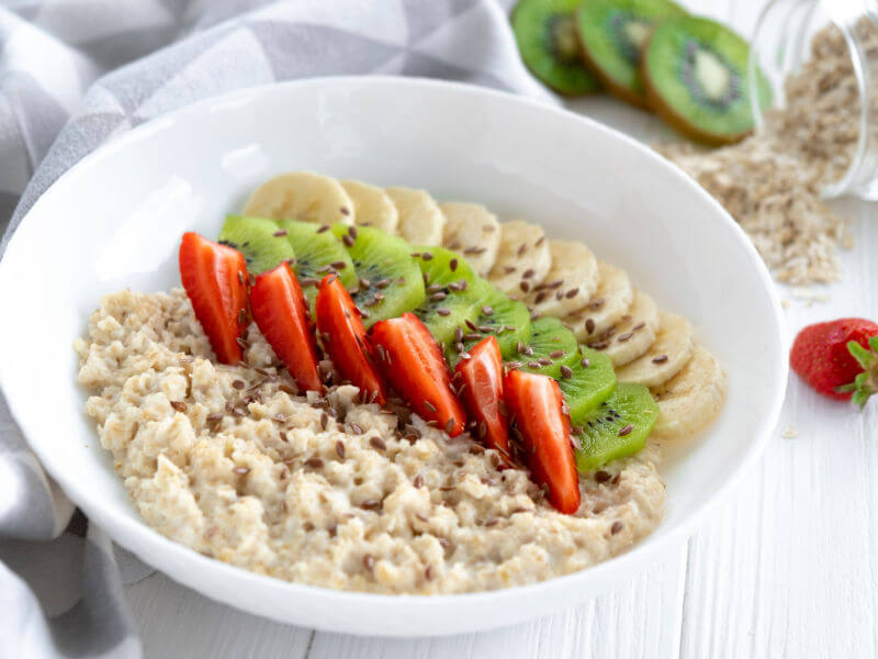 Prato branco com mingau de aveia com linhaça e morango, kiwi e banana