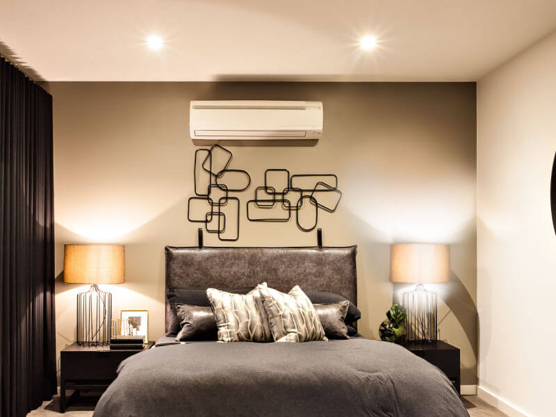 Quarto com cama cinza, cortina escura e luminárias