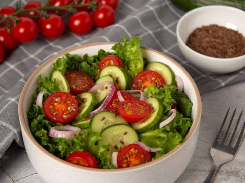 Recipiente branco com salada de alface, tomate, cebola e pepino
