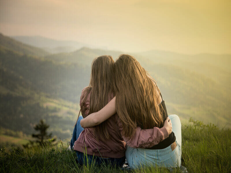 Duas mulher se abraçando e olhando para paisagem