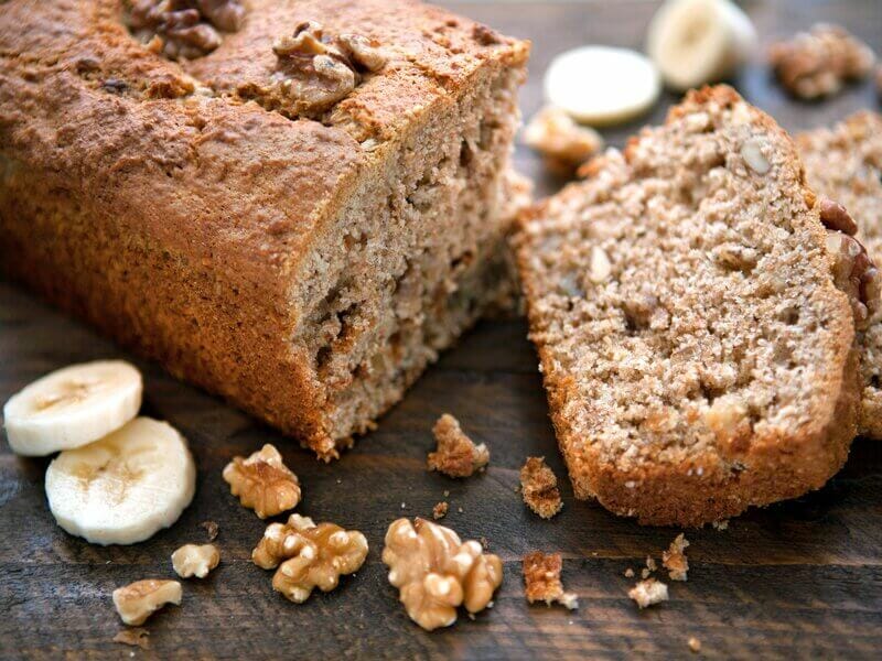Bolo de nozes cortado em um pedaço em cima de uma mesa de madeira com pedaços de nozes