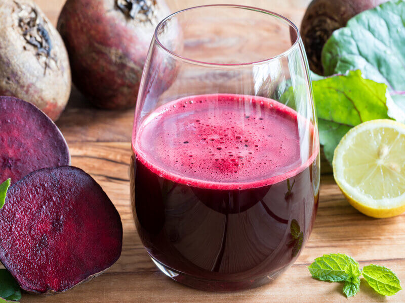 Copo de vidro com suco de beterraba em cima de uma mesa de madeira