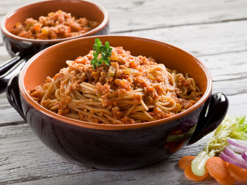 Prato fundo marrom com macarrão ao molho bolonhesa
