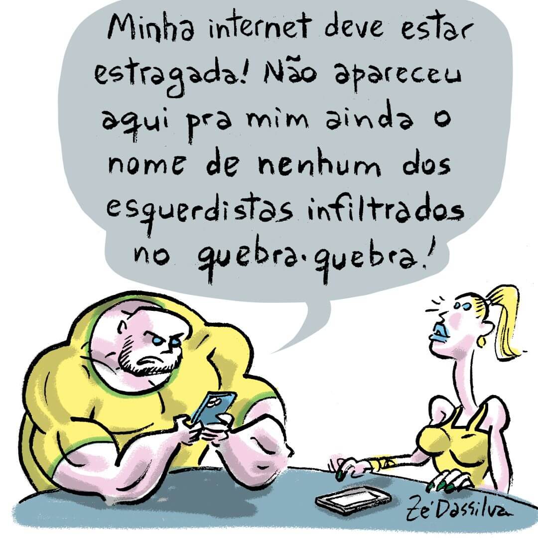 Na imagem aparecem um homem e uma mulher vestidos com roupas verde-amarelas sentados à mesa. O homem é musculoso, está usando o celular e diz "Minha internet deve estar estragada! Não apareceu aqui pra mim ainda o nome de nenhum dos esquerdistas infiltrados no quebra-quebra"!