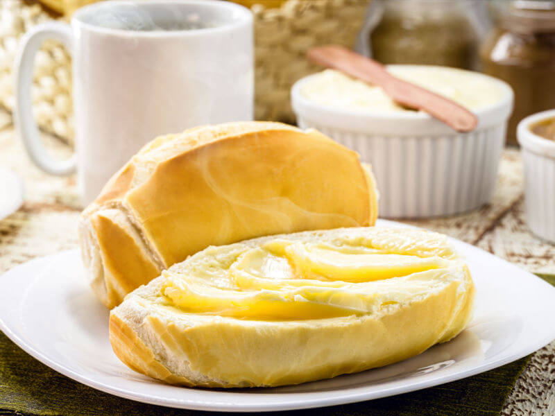 Pão francês com manteiga em prato branco