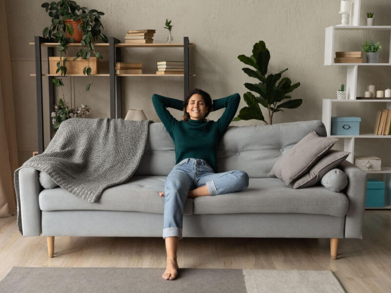 Quarto com tons branco, cama com lençóis brancos e almofadas verdes, espelho e plantas