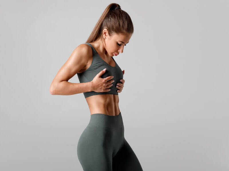 Mulher com roupa de academia olhando para o abdômen