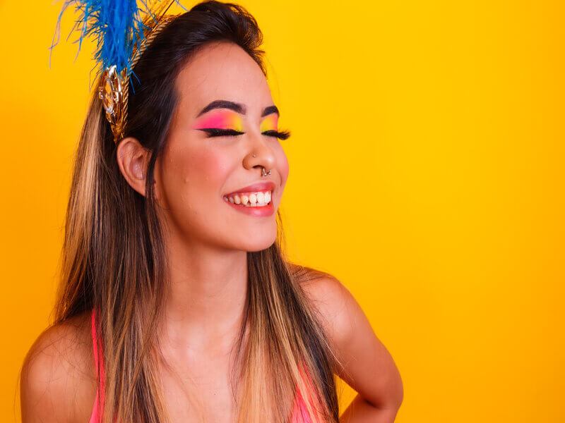 Mulher sorrindo com maquiagem colorida e tiara dourada