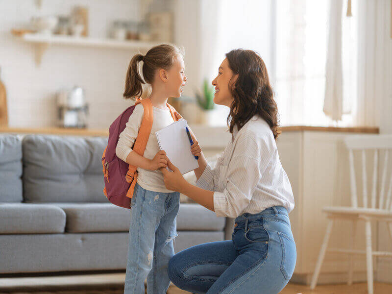 Mulher conversando com menina com mochila nas costas