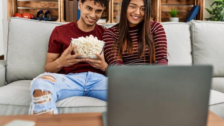 Jovens com balde de pipoca assistindo filmes