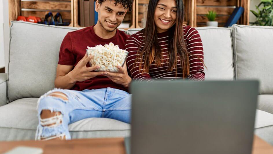 Jovens com balde de pipoca assistindo filmes