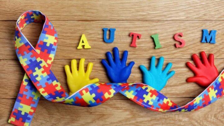 Conceito de consciência do autismo com mãos coloridas no fundo de madeira