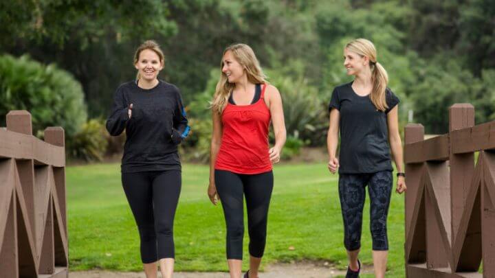 Três mulheres sorridentes caminhando em capa