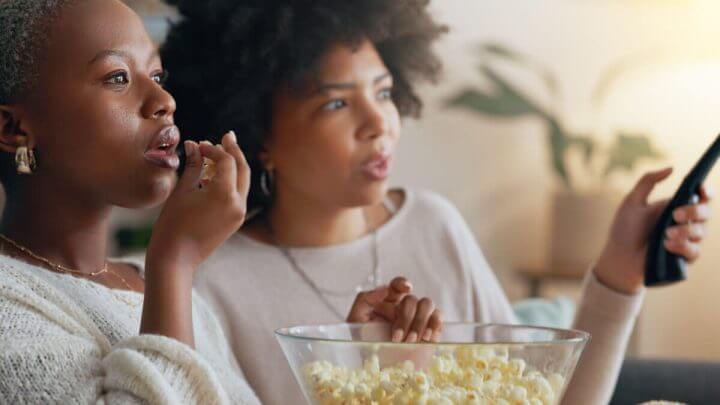 Duas mulheres comendo pipoca e assistindo a um filme