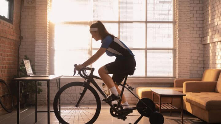 Mulher ciclista se exercitando em casa