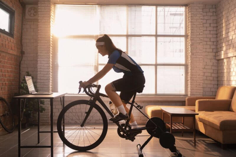 Mulher ciclista se exercitando em casa