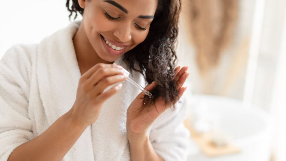 mulher passando óleo no cabelo