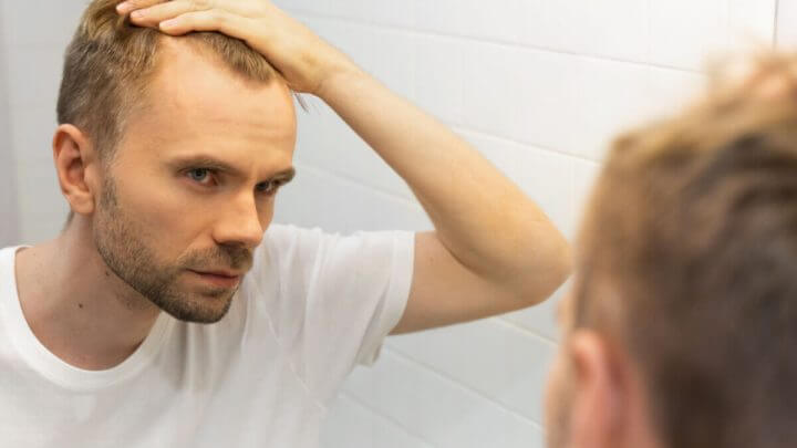 Homem olhando o cabelo pelo espelho