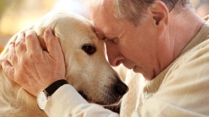 Um senhor abraçado com seu cão