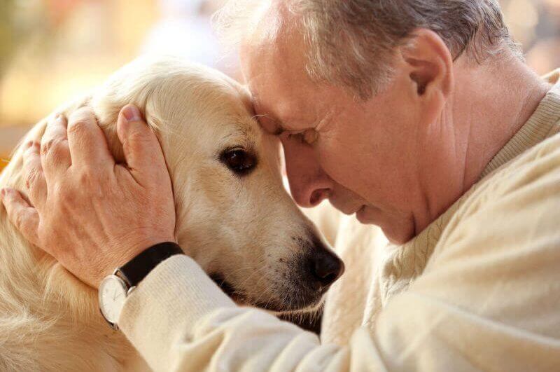 Um senhor abraçado com seu cão