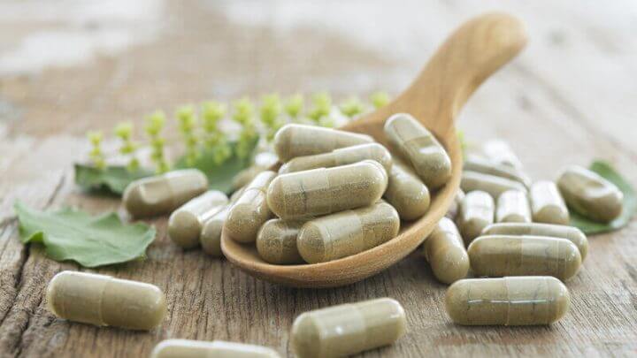 Cápsulas de suplementos alimentares em cima de uma mesa de madeira
