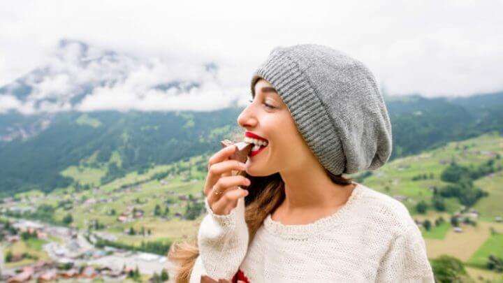 Mulher comendo chocolate em viagem nas montanhas