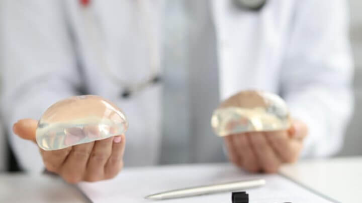 Médico mostrando implantes de silicone para o seio
