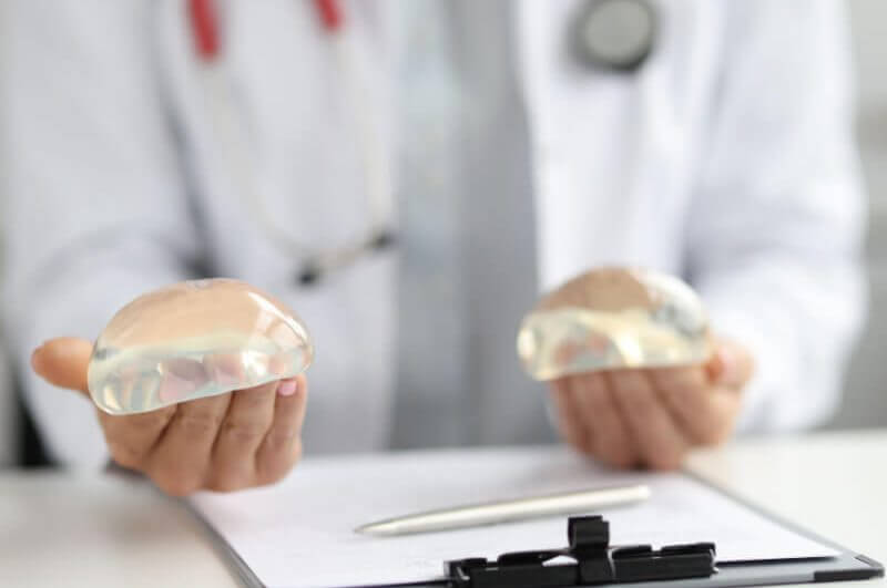 Médico mostrando implantes de silicone para o seio