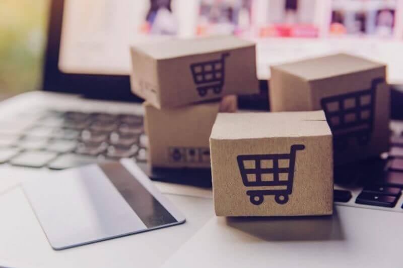caixas de papel ou pacote com o logotipo do carrinho de compras e cartão de crédito no teclado do laptop