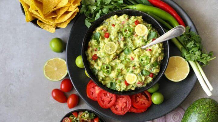 Tigela de guacamole mexicano tradicional, nachos e guacamole ingredientes: abacate, cebola, coentro, tomate pimenta e limão