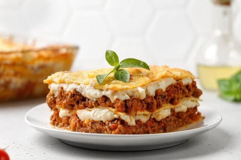 Lasanha com carne moída e molho branco em cima de um prato branco