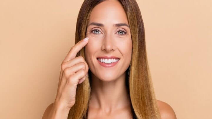 Mulher sorrindo com o dedo apontando para o olho