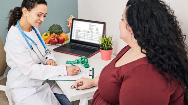 Médica e paciente em consultório. Médica escreve em papel