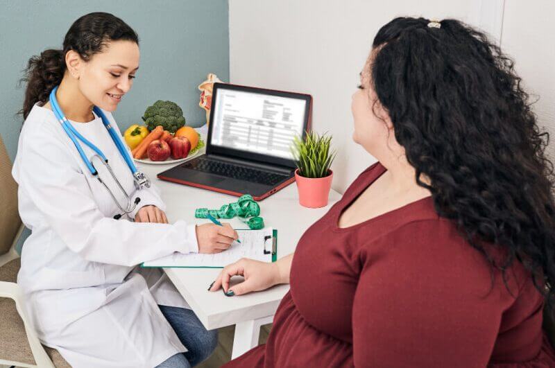 Médica e paciente em consultório. Médica escreve em papel
