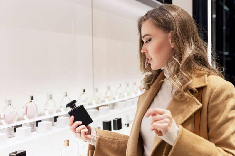 Mulher escolhendo perfume na prateleira