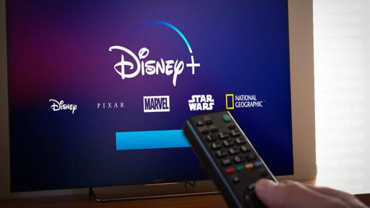 Logo do Disney+ em uma televisão com pessoa segurando um controle remoto