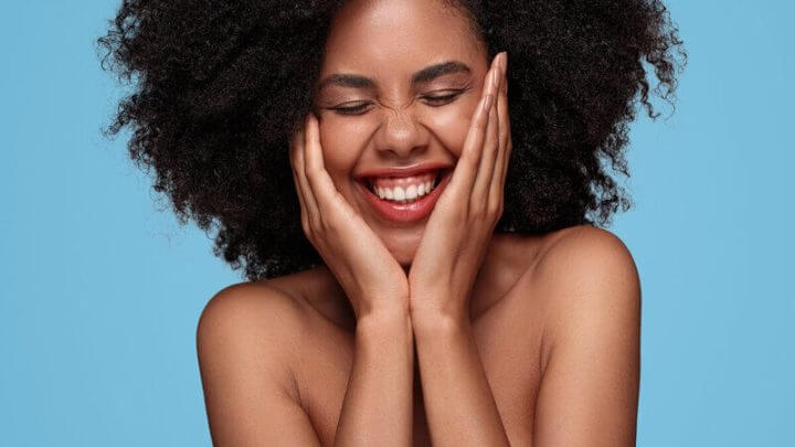 Mulher sorrindo com as mãos no rosto