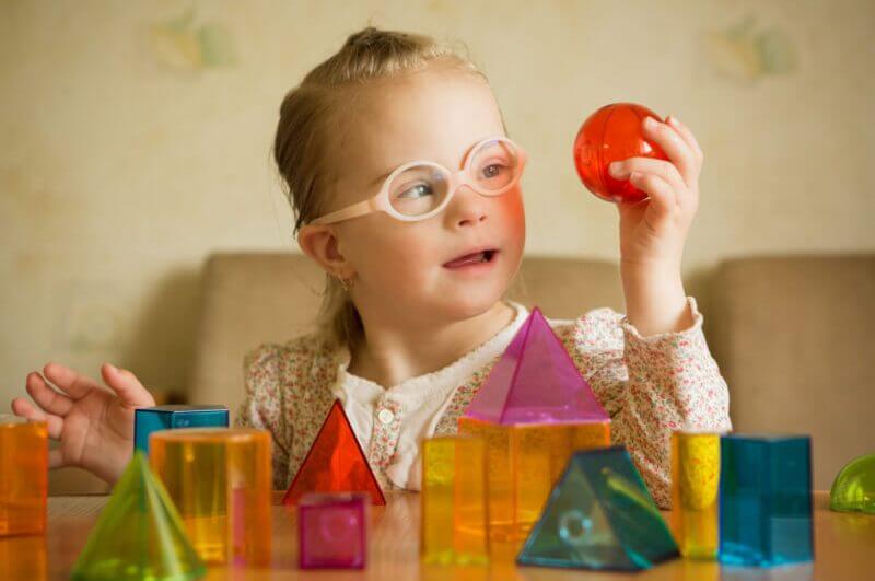 Menina com síndrome de Down jogando com formas geométricas