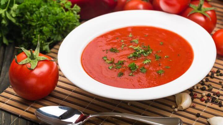 Sopa de tomate polvilhada com coentro picado em um prato branco