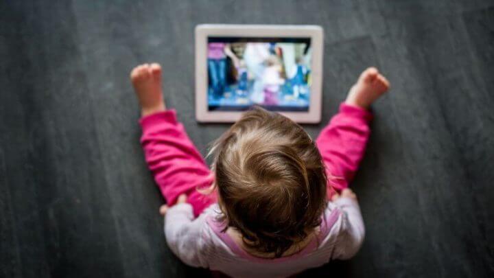criança sentada no chão olhando para a tela do tablet