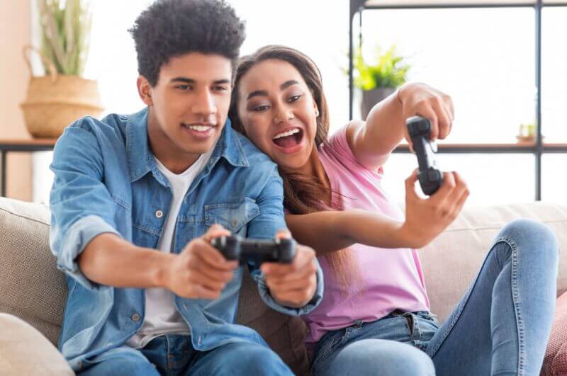 Menino e menina jogando videogame sentados no sofá