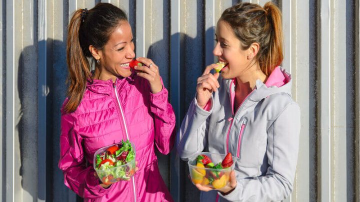 Duas mulheres sorrindo e segurando frutas