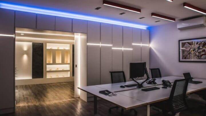 Escritório moderno e iluminado com mesa, cadeiras e computador.