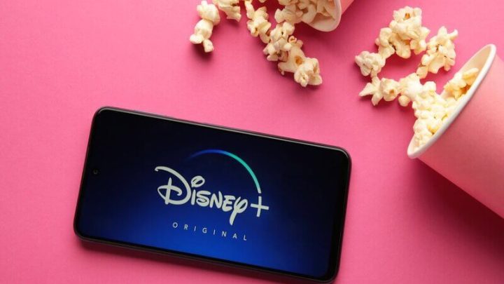 Logo do Disney Plus e um celular com copos de pipoca rosa ao lado