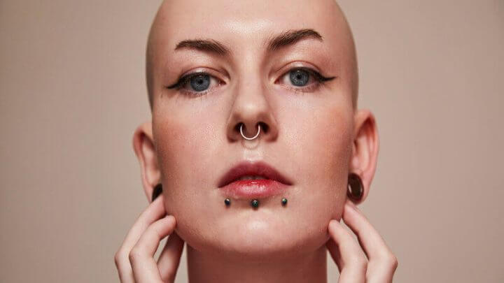 Mulher com piercing no nariz e no queijo com as mãos no rosto
