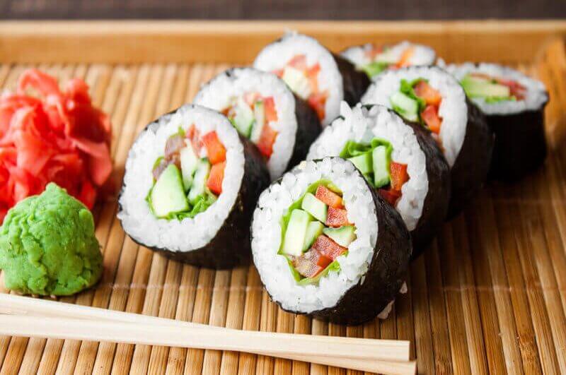 Sushis com pepino e tomate em cima de um tapete de bambu