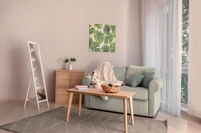 Sala de estar com parede rosa, sofá cinza e mesa de centro de madeira