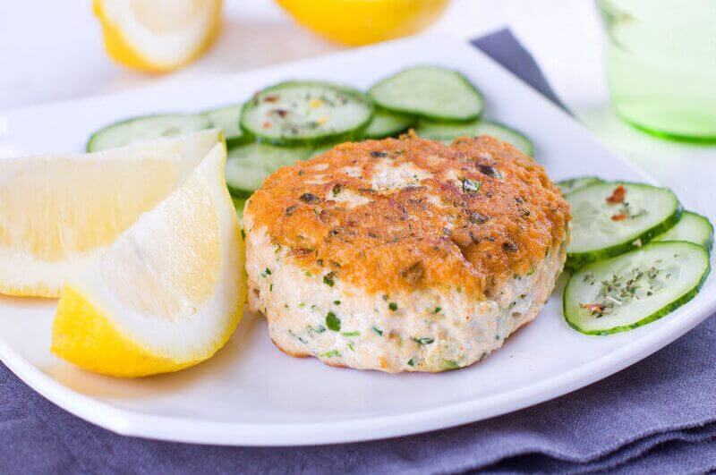 Prato branco com hambúrguer de salmão, rodelas de pepino e limão