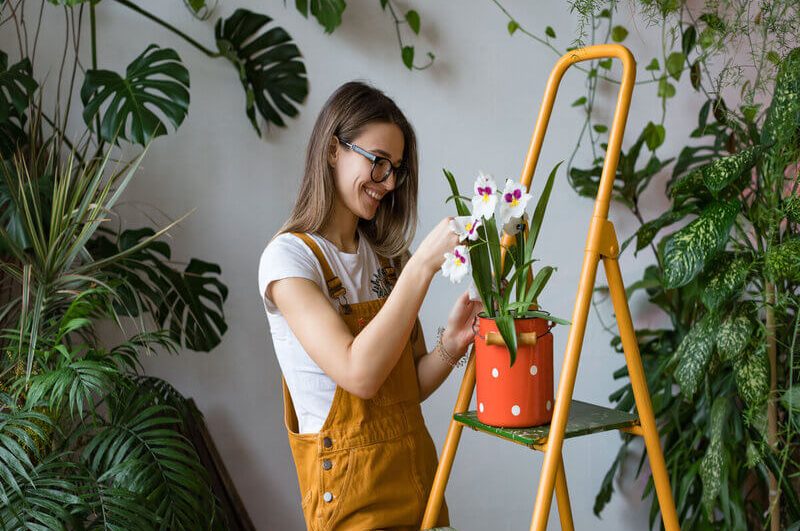 Mulher sorridente cuidando de uma orquídea